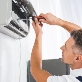 handsome-adult-man-repairing-air-conditioner-with-screwdriver